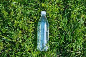 plastic bottle of fresh water on green grass photo