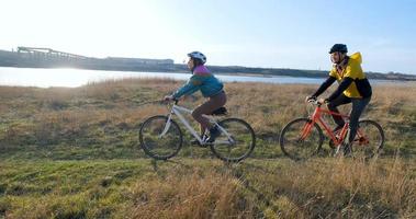 un par de hombres y mujeres montan en bicicleta cerca del río durante la puesta de sol foto