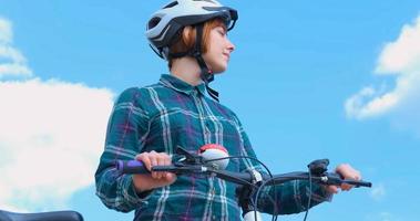 Young woman bicycle rider in helmet in sunny summer day photo