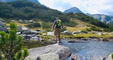 joven viajero masculino en las montañas sentado cerca del río foto