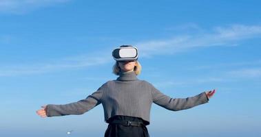 Young handsome female with virtual reality glasses outdoor on the beach against sunny blue sky photo