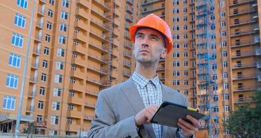 portrait of construction specialist in orange helmet and safety vest against big building photo