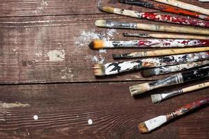 Brushes for painting lie on the old wooden rustic table in the artist's studio photo