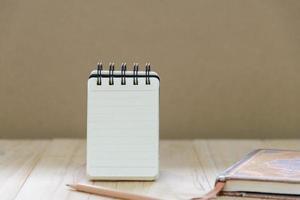 Small note book paper or notepad stand for writing information with pencil and book on wood table photo