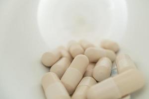 White capsules inside opened supplement plastic bottle. Several white capsules in the white bottle. photo