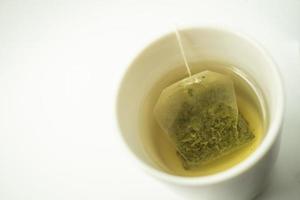 Green tea bag in a cup. Cup of aromatic green tea on white background. Cup with green tea in isolated. photo