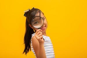 Portrait of happy little Asian child with magnifying glass. photo