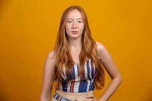 Portrait of beautiful cheerful redhead girl with flying hair smiling laughing looking at camera over yellow background. photo