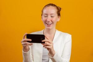Young, confident, successful and beautiful business redhead woman with the smartphone on yellow. Occupation, career, job concept. photo