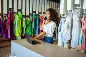 Smiling Latin designer contacts client about online order in fashion shop. photo