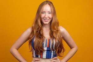 Portrait of beautiful cheerful redhead girl with flying hair smiling laughing looking at camera over yellow background. photo