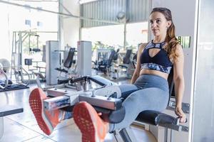 Cute young woman during a leg workout in a gym photo