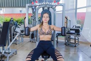 Girl training pectoral in gym apparatus photo