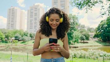 Latin woman using smartphone in the park. Brazilian girl. photo