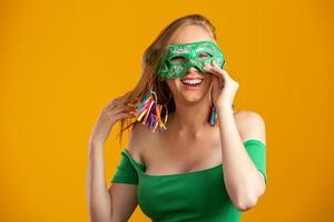 hermosa mujer vestida para la noche de carnaval. mujer sonriente lista para disfrutar del carnaval con una máscara colorida. foto