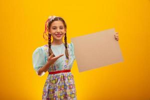 Child in typical clothes of famous Brazilian party called Festa Junina in celebration of Sao Joao. Beautiful girl on yellow background. photo