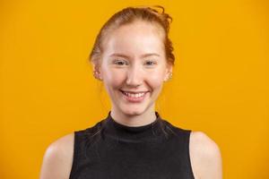 Portrait of beautiful cheerful redhead girl smiling laughing looking at camera over yellow background. photo