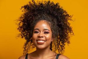 Beauty portrait of african american woman with afro hairstyle and glamour makeup. Brazilian woman. Mixed race. Curly hair. Hair style. Yellow background. photo