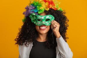 hermosa mujer vestida para la noche de carnaval. mujer sonriente lista para disfrutar del carnaval con una peluca y una máscara coloridas foto