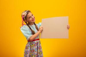 Child in typical clothes of famous Brazilian party called Festa Junina in celebration of Sao Joao. Beautiful girl on yellow background. photo