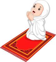 Muslim girl sitting on the prayer rug while praying