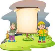 dos lindos niños con la linterna ramadhan están parados cerca de la pancarta en blanco en el jardín vector