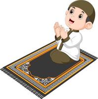 the boy with the brown cap is praying on the brown prayer rug