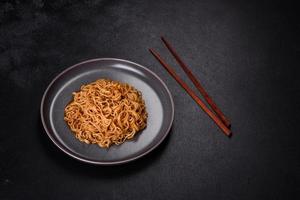 Buckwheat flour noodles with sauce, sesame, herbs and spices on a dark concrete background photo