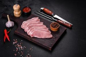 Raw fresh pork meat sliced on a wooden cutting board photo