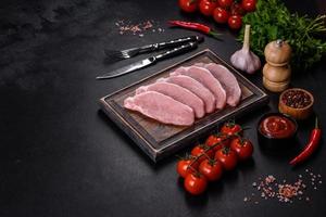 Raw fresh pork meat sliced on a wooden cutting board photo