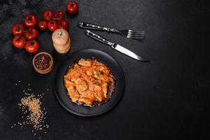 Teriyaki chicken with sauce, sesame, herbs and spices on a dark background photo