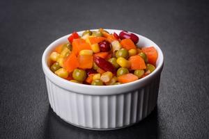 A mixture of chopped vegetables paprika, corn, peas in white plate photo