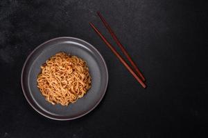 Buckwheat flour noodles with sauce, sesame, herbs and spices on a dark concrete background photo