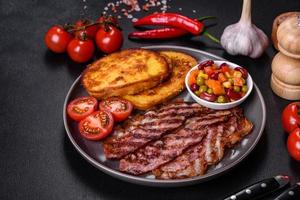 Slices of delicious grilled bacon with croutons fried in egg with spices, salt, vegetables and herbs photo