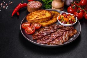 Slices of delicious grilled bacon with croutons fried in egg with spices, salt, vegetables and herbs photo