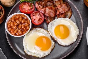 A delicious nutritious healthy breakfast with fried eggs, bacon, beans, a glass of juice, oat cookies, milk and jam photo