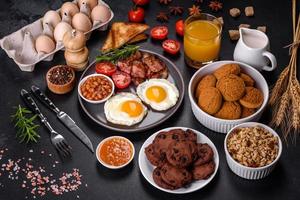 A delicious nutritious healthy breakfast with fried eggs, bacon, beans, a glass of juice, oat cookies, milk and jam photo