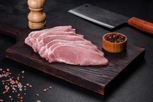 Raw fresh pork meat sliced on a wooden cutting board photo