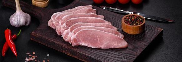 Raw fresh pork meat sliced on a wooden cutting board photo