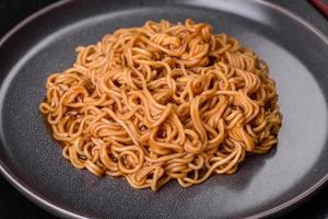 Buckwheat flour noodles with sauce, sesame, herbs and spices on a dark concrete background photo