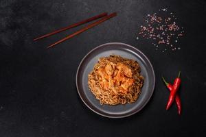 Thai noodle and chicken plate on a black concrete background with Chinese chopsticks and copy space photo