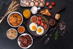 A delicious nutritious healthy breakfast with fried eggs, bacon, beans, a glass of juice, oat cookies, milk and jam photo