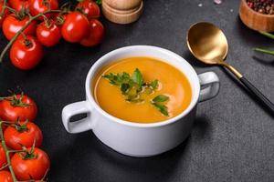Delicious fresh pumpkin puree soup decorated with parsley in a white plate photo