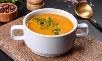 Delicious fresh pumpkin puree soup decorated with parsley in a white plate photo
