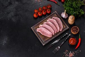 Raw fresh pork meat sliced on a wooden cutting board photo