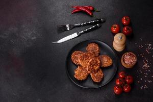 Fish cakes. Fish patties. Fried cutlets of minced fish on a black plate photo