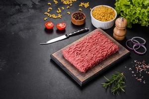 Fresh raw mince with spices and herbs on a dark concrete background photo