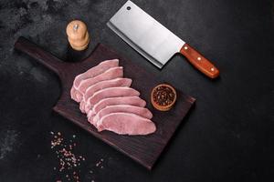 Raw fresh pork meat sliced on a wooden cutting board photo