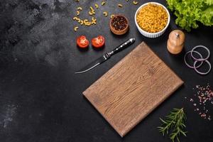 A wooden cutting board with a kitchen knife with spices and herbs photo