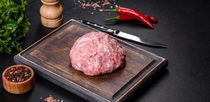 Ground meat with ingredients for cooking on black background photo